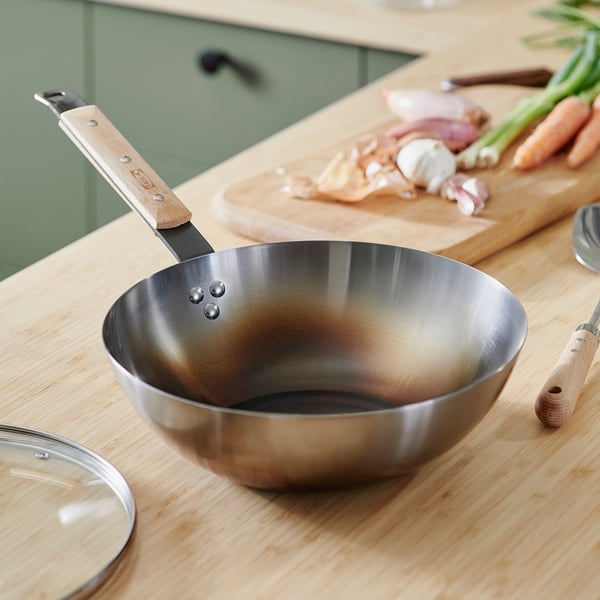 Metal wok with wooden handle and chopped veggies on wooden table. Or wok with wooden handle and chopped veggies on table.