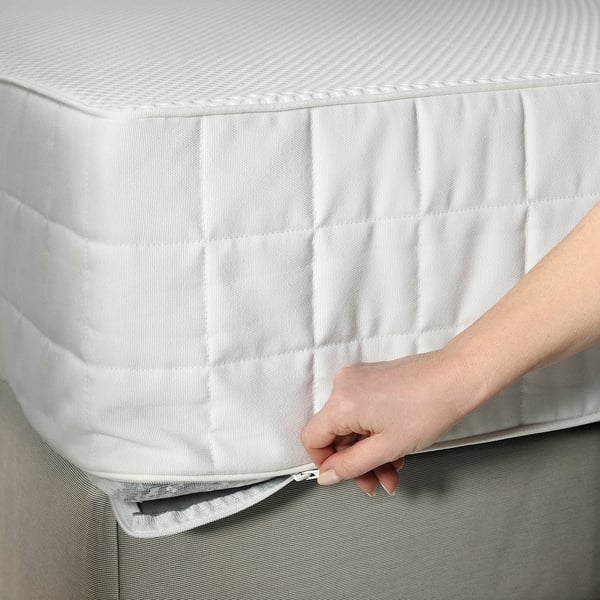 A hand zips a bed mattress protector, ensuring cleanliness and comfort with easy removal for washing.