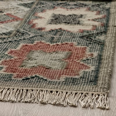 A VESTERVIG rug, handmade with intricate patterns in soft colors. It is rectangular, featuring a flat-woven wool design on a cotton base.