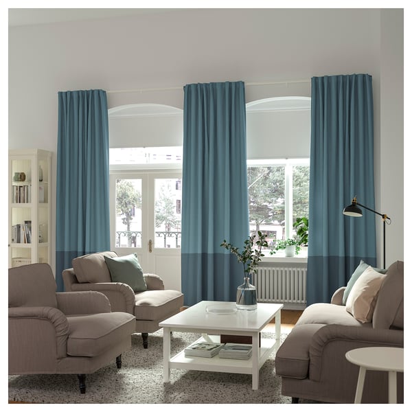Living room with modern gray sofas, white coffee table, blue curtains, and floor lamp; large window.