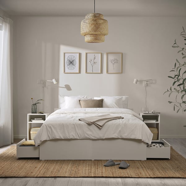 Minimalist bedroom with white VIHALS bed, built-in storage, jute rug, pendant light, botanical prints, and bed lamps.