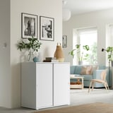 Minimalist living room, white storage cabinet, couch & chair, natural light.