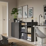 Home office with black storage unit, desk, plants, and art.