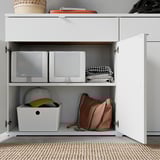 Great storage cabinet, white with two shelves, organized boxes, hat, and bag.