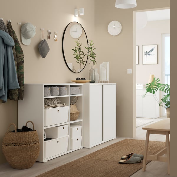 Modern entryway with white VIHALS storage units, mirror, and hangers. Neatly organized with beige decor and accessories.