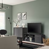 Modern living room with teal walls, black tv bench, gray sofa, and rug.