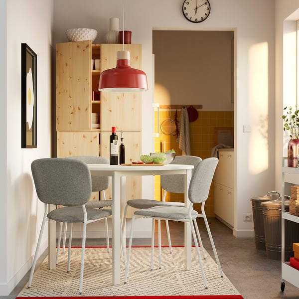 Modern dining setup with VIHALS round table, white legs, gray chairs, red pendant light, fruit, wine.