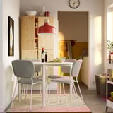 Modern dining setup with VIHALS round table, white legs, gray chairs, red pendant light, fruit, wine.