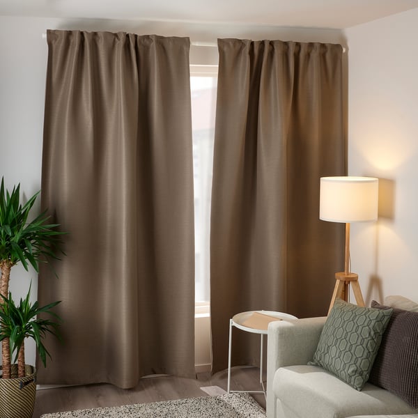 Large living room with brown VILBORG curtains, white lamp, green plant, and light grey couch with hexagonal pillows.