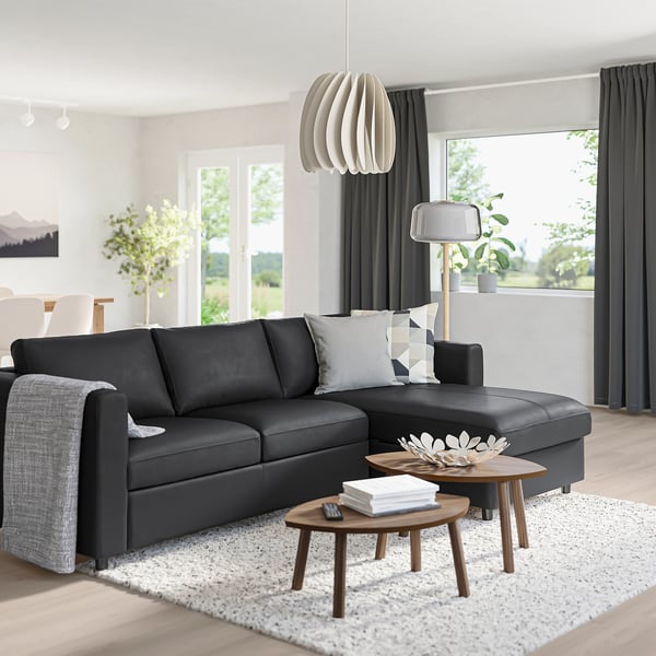 Modern living room with black VIMLE sectional, wooden tables, white rug, and large window.