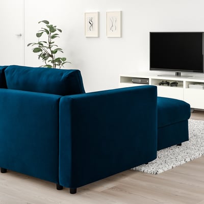 Blue velvet VIMLE sofa with chaise against white wall, tv nearby.