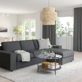 Modern living room with gray sectional sofa, glass coffee table, and large pendant light.