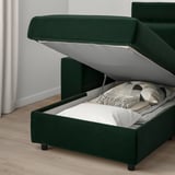 Green sofa bed with storage open, revealing white mattress and gray blankets. Highlights the sofas dual functionality and storage feature.