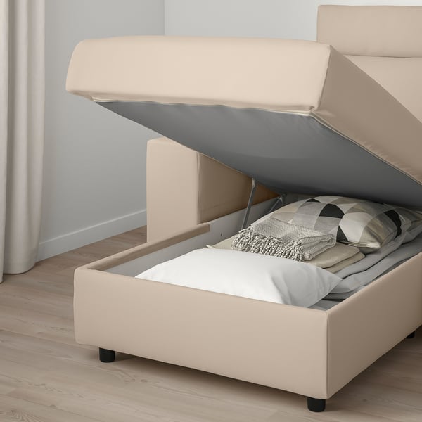 Sofa with raised storage seat, showing plush cushions and folded blanket inside.