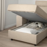 Bed or sofa with storage compartment open, showing pillows and blanket inside. Lid stays open for easy access.