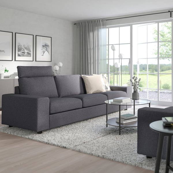 Gray VIMLE sofa, ottoman, glass coffee table, large window. Minimalist decor.