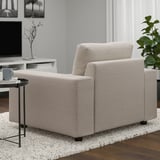 Modern living room with beige VIMLE sofa chair, black side table, grey rug, plant, and tv.