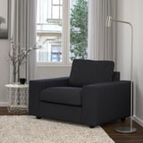 Modern black armchair beside a tall lamp, on a light rug.