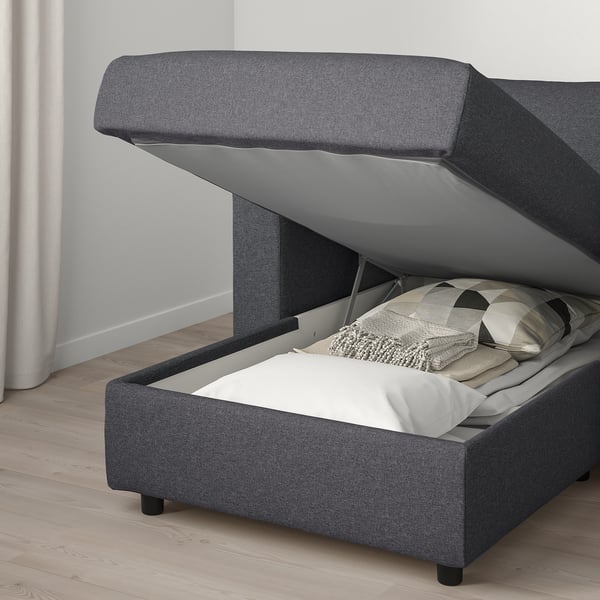 Modern grey upholstered sofa bed with storage, opened to reveal cushions.