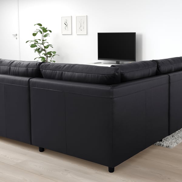 Modern living room with large black VIMLE sectional sofa, tv, plant, and decor. Dark cushions with light wooden floor.