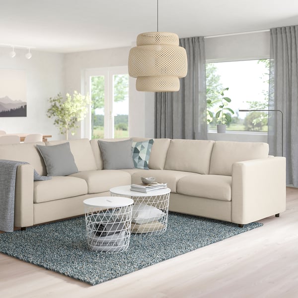 Beige VIMLE sectional sofa with plush cushions and blue pillows, large pendant lamp, magazines on table.