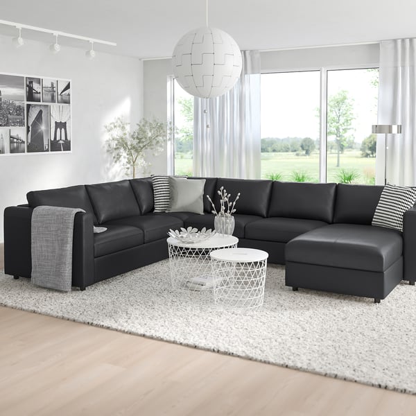 Black leather VIMLE sectional sofa with houndstooth throws in bright room, spacious feel.