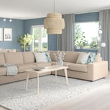 Modern living room with VIMLE sofa, coffee table, grey curtains. Natural light, cozy decor, blue/white pillows, rug, pendant lamp, plants.