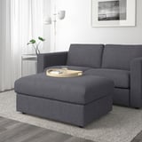 Modern gray sectional sofa with ottoman, wooden tray, and side lamp. Storage and drink holder.