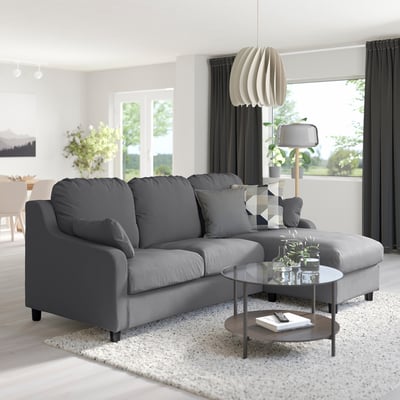 Modern living room with large gray l-shaped VINLIDEN sofa, patterned cushions, glass coffee table, and hanging lamp.