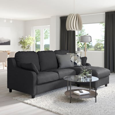 Modern living room with VINLIDEN grey sectional, rug, glass table, lamp, and large windows.