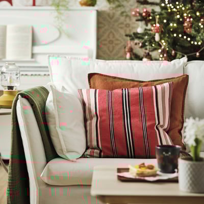 Living room with red striped cushion, festive pillows, and decorated christmas tree.