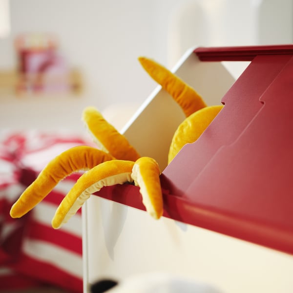 Orange plush tent on red toy storage. Fun and colorful kids play equipment.
