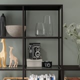 Shelf with glass panels displaying decorative items: vase, bowl, cameras, giraffe figurines, and books. Wall-mounted for stability.