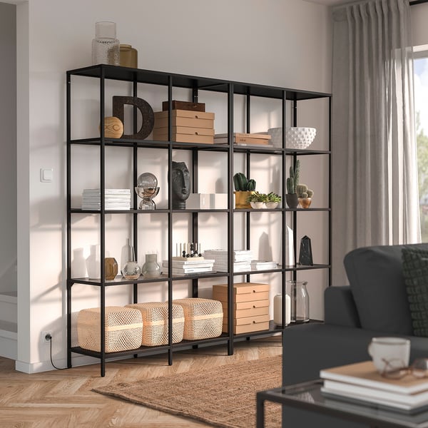 Modern living room with VITTSJÖ bookshelf, grey chair, and windows.