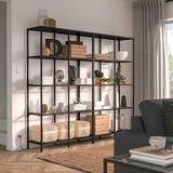 Modern living room with VITTSJÖ bookshelf, grey chair, and windows.