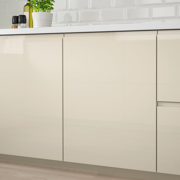 Modern kitchen cabinets with glossy beige finish, featuring sleek integrated handles for easy access.