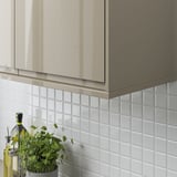 Modern kitchen with gray cabinets; white tiles and a plant on the counter.