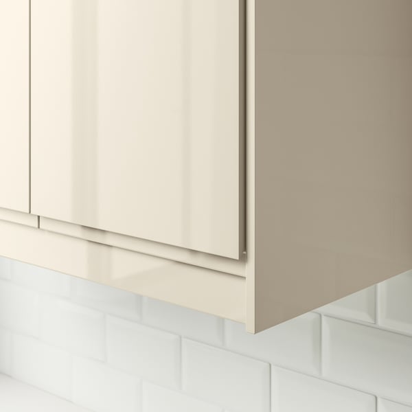 Modern kitchen cabinet with glossy beige finish and integrated handle. Used to cover lighting units and cords under wall cabinets.
