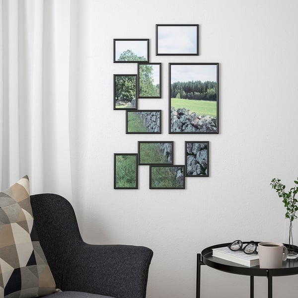 Black YLLEVAD frames with nature photos on wall, armchair, side table, window with curtains.