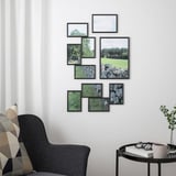 Black YLLEVAD frames with nature photos on wall, armchair, side table, window with curtains.
