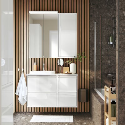 Modern white vanity with mirror, 4 drawers, marble top, semi-recessed sink, glass shower door.