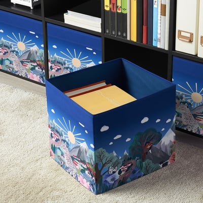 Blue ALPTALL boxes with colourful designs for kallax shelving, neatly storing items among books and folders.