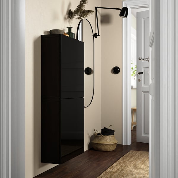Black BESTÅ storage unit, tall, slim, modern, fits narrow space, with shelves and hanging lamp.