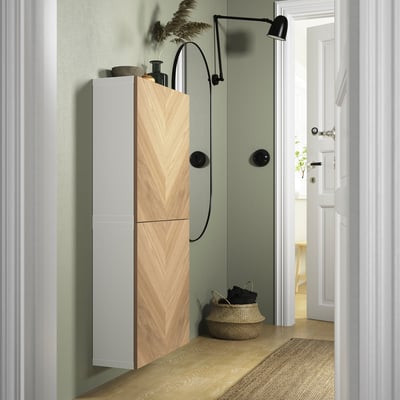 White BESTÅ cabinet with chevron doors, corner-placed, lit, basket with logs.
