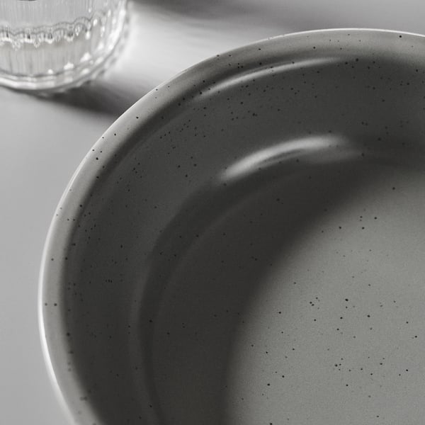 Close-up of a grey stoneware bowl with speckles. Smooth, speckled surface, simple design, robust feel.