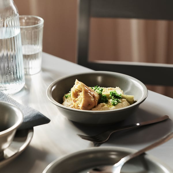 A dishes set a stoneware bowl with food and a glass of water, ideal for quick meals or formal dinners.