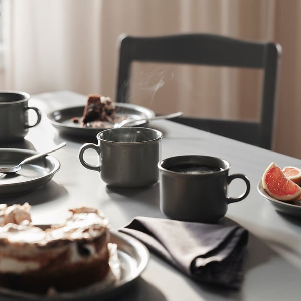 DAGGASTER grey stoneware mugs and plates. Coffee and cake on table. Mugs smaller than plates, semi-matte finish.