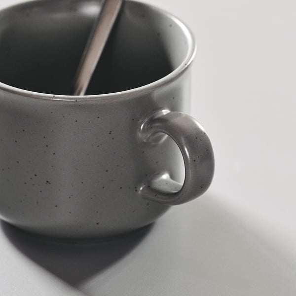 Cup close-up, textured grey mug with handle, metal spoon inside
