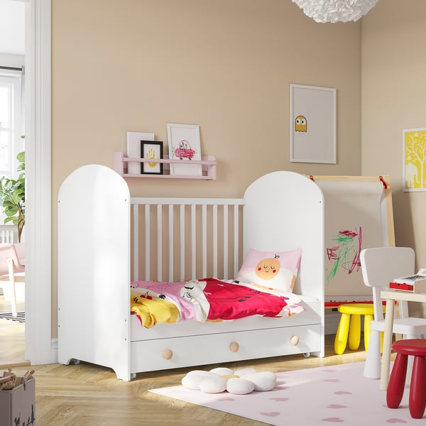 Kids room with GONATT cot, bright bedding, pink rug, yellow stool, tables, frames, & creative station.