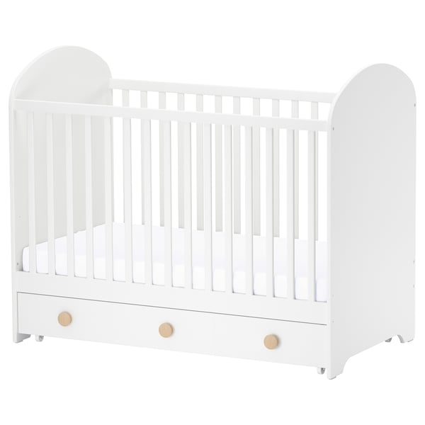 White GONATT baby crib with wooden knobs, arched ends, and bottom storage drawer.